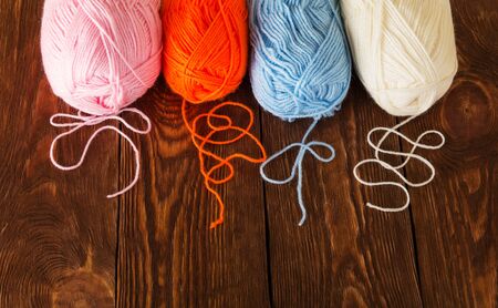 Skeins of yarn of different colors lie on brown wooden tableの写真素材