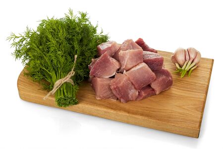 Pieces of fresh pork, bunch of dill and garlic on chopping Board isolated on white backgroundの写真素材