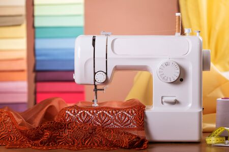 Household electric sewing machine in operation, on background of tissue samplesの写真素材