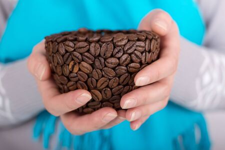 Improvised Cup made from coffee beans in woman's handsの写真素材