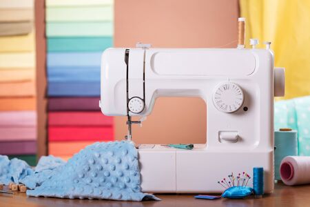 Sewing machine and cloth in work, sewing supplies on wooden tableの写真素材
