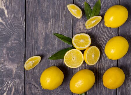 Lots of big yellow lemons and pieces, on grey wooden surfaceの写真素材