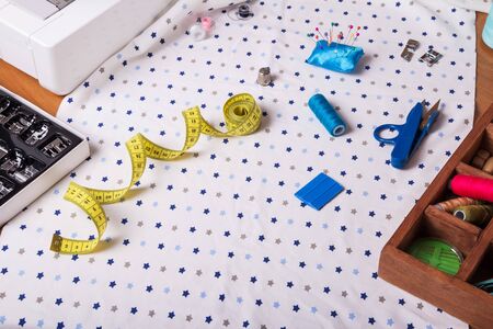 Centimeter, thimble, scissors and other sewing accessories on piece of light fabricの写真素材