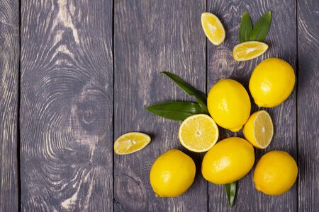 Few ripe yellow lemons and sliced pieces on an old wooden surfaceの写真素材