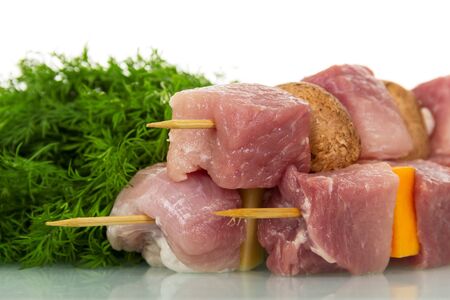 Pieces of raw pork, vegetables, mushrooms on wooden skewers and fennel isolated on white background.の写真素材