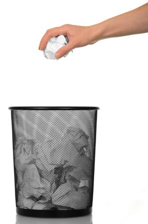 A basket of paper waste and a female hand holding a ball of crumpled paper isolated on white background.の写真素材