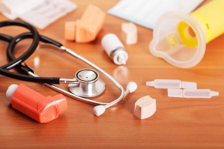 Inhalers aerosol, stethoscope, aerochamber, packaging and medicines on the background of the table.の写真素材