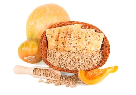 Basket with crispy biscuits and fried sunflower seeds, wooden scoop, whole pumpkin and slice isolated on white background.の写真素材