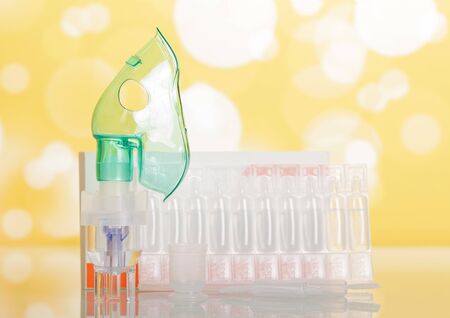 Adapted for inhalation with a mask and spare ampoules on a yellow flickering backgroundの写真素材