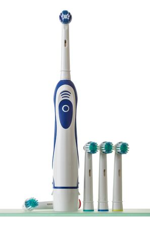 Electric toothbrush with set of interchangeable tips on glass shelf isolated on white backgroundの写真素材