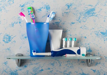 Manual brushes of different colors in glass and electric with replaceable nozzles, on glass shelfの写真素材