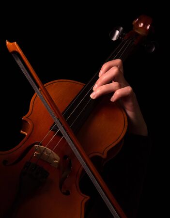 Bow and female fingers on violin strings isolated on black backgroundの写真素材