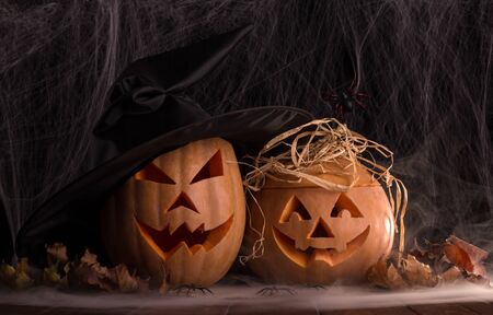 Two halloween pumpkins and spiders in the smoke against the backdrop of a dark webの写真素材