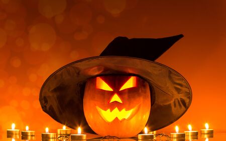 Glowing Halloween pumpkin and candles on ominous orange backgroundの写真素材