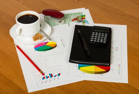 Coffee Cup, calculator, pen, Notepad, sheets of paper with the accounts and diagrams, other stationery on the desktop background.の写真素材