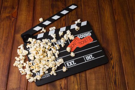 Black with white letters party poppers, popcorn and movie tickets on a background of dark wood.の写真素材