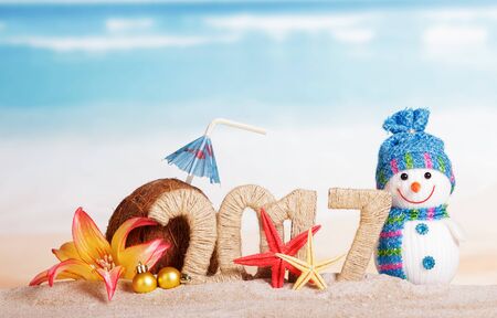 The inscription 2017 in the sand with a Christmas snowman, coke and starfish on a background of oceanの写真素材
