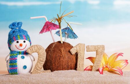 Christmas snowman, coconut with umbrellas and the inscription 2017 in the sand against the seaの写真素材
