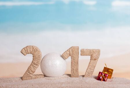 Christmas ball and the inscription 2017 in the sand against the seaの写真素材