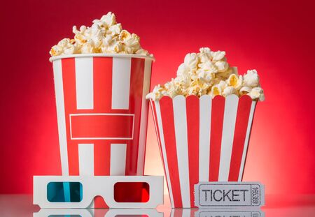 Large and small popcorn boxes, a ticket to the movies and 3d glasses on a red backgroundの写真素材
