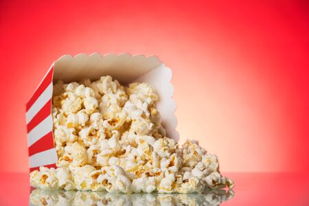 Loose popcorn in striped box on a bright red backgroundの写真素材