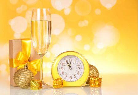 Christmas gift with a bright ribbon, champagne, christmas watch on a yellow backgroundの写真素材