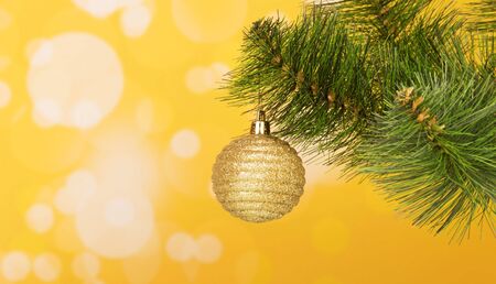 Yellow ball hanging on the Christmas tree on a yellow backgroundの写真素材