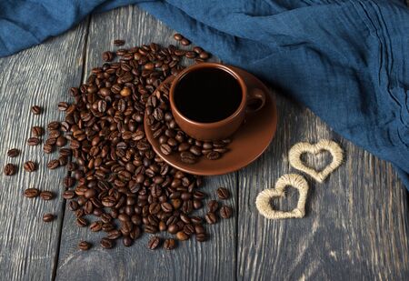 Cup of coffee and scattered grains, next to fabric and small heartsの写真素材