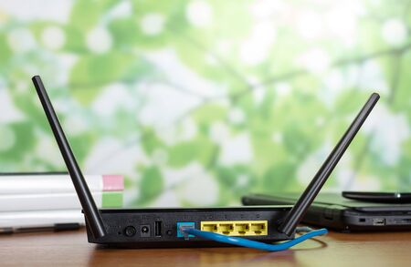 Internet cable connected to the router, near on wooden table modern communication gadgetsの写真素材