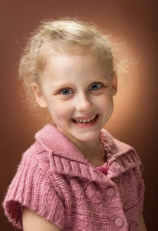 Adorable girl with blond curly hair smiling cheerfullyの写真素材
