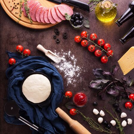 Finished dough in bowl and set of products for cooking pizza on work surfaceの写真素材