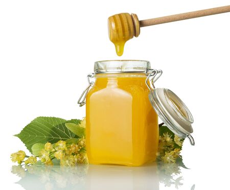 Trickle of golden honey flows from beater into jar, isolated on white backgroundの写真素材