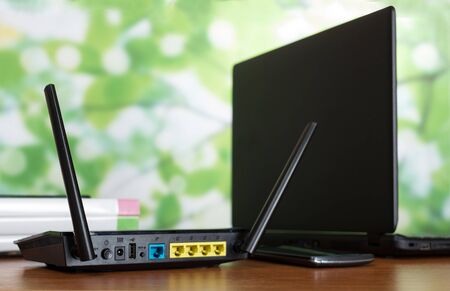 WiFi router, cable connection socket and laptop on work tableの写真素材