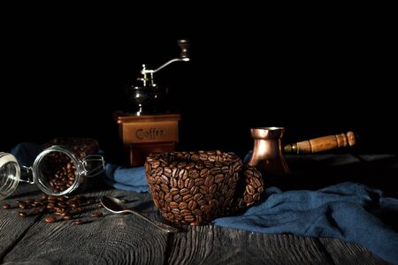 Improvised Cup made from coffee beans, hand mill on blue fabric, isolated on black backgroundの写真素材