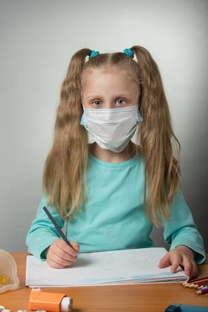 Little sick girl in gauze bandage draws sitting at tableの写真素材
