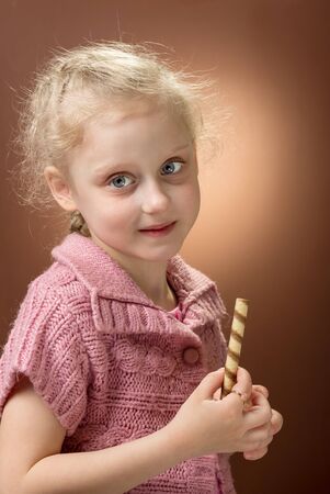 Charming blonde girl smiles and holds sweets in her handの写真素材