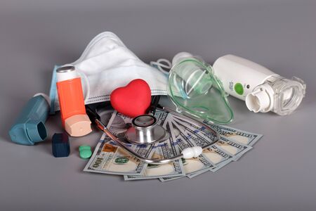 Inhalers and mask, stethoscope, money for diagnostics and treatment, on gray backgroundの写真素材