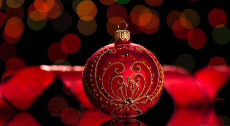Beautiful Christmas toy is decorated with a gold pattern and rhinestones, on shimmering dark red backgroundの写真素材
