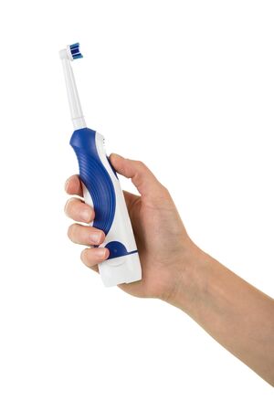 Women's fingers pressed button of an electric toothbrush isolated on white backgroundの写真素材