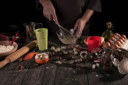 Baker's hands whipped with whisk quail eggs in bowl isolated on black backgroundの写真素材