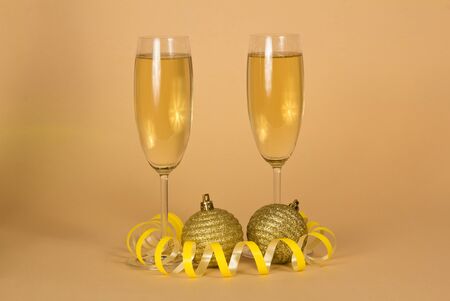 Two glasses with champagne, beautiful new year toys and serpentine, on beige backgroundの写真素材