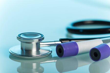 Medical stethoscope and vacuum tubes for blood collection on a blue background.の写真素材
