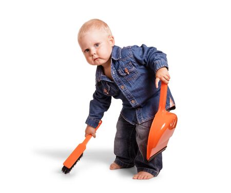 Serious kid holds scoop and broom, isolated on white backgroundの写真素材