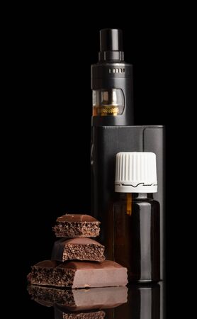 Electronic cigarette and bottle with fragrant liquid, chocolate segments, isolated on black backgroundの写真素材