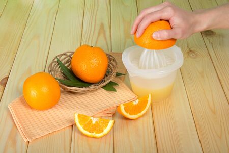 Juicer, whole oranges and pieces on  wooden tableの写真素材