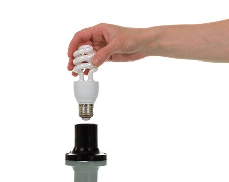 In a female hand a compact fluorescent light bulb, the cartridge is isolated on a white background.の写真素材
