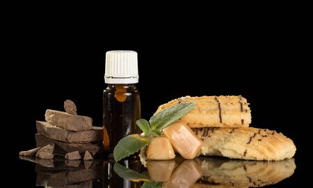 Bottles with aromatic liquid for smoking, biscuits and chocolate isolated on black backgroundの写真素材
