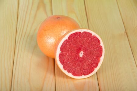 Whole grapefruit and sliced slices on a wooden tableの写真素材