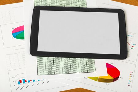 Tablet, sheets of paper account and charts on the desktop background.の写真素材