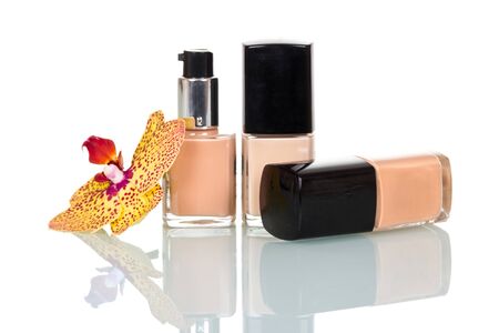 Three bottles with the foundation of different tones and an orchid flower isolated on white background.の写真素材